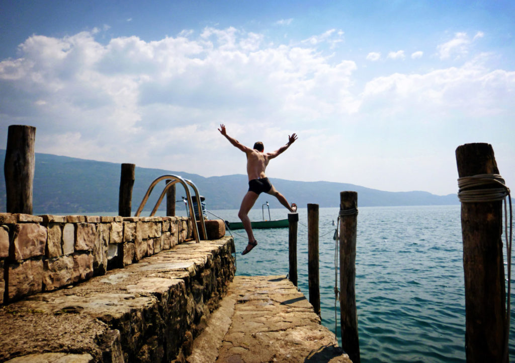 Homme sautant de joie dans un lac