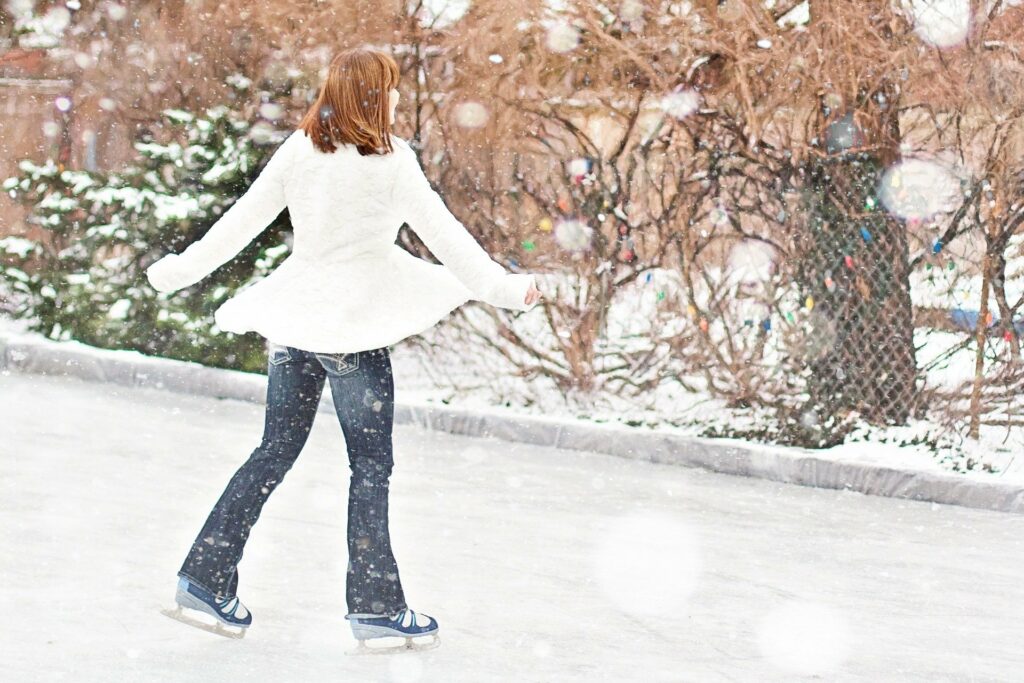 femme en manteau blanc qui patine sous la neige