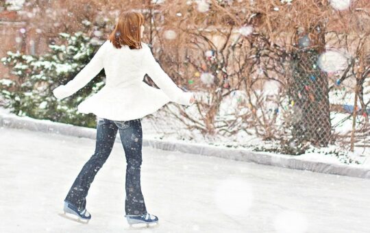 femme en manteau blanc qui patine sous la neige