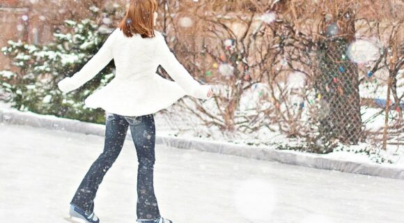 femme en manteau blanc qui patine sous la neige