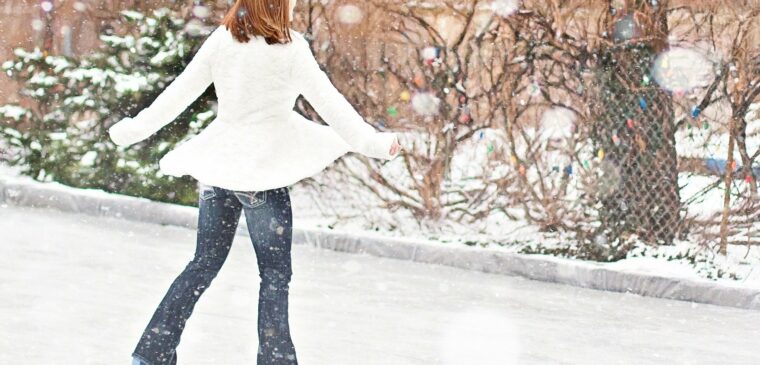 femme en manteau blanc qui patine sous la neige