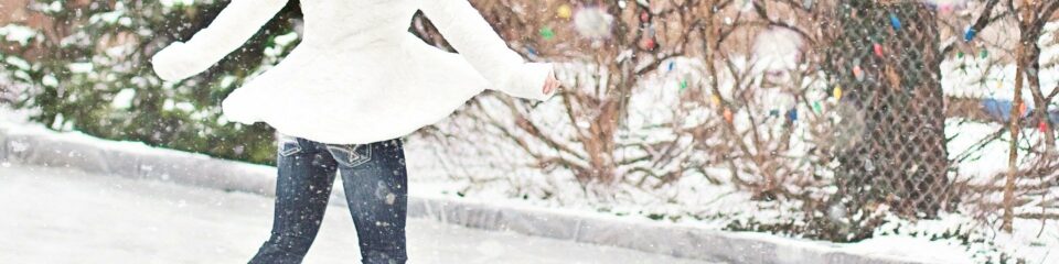 femme en manteau blanc qui patine sous la neige
