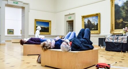 personnes couchées sur structure bois devant tableaux