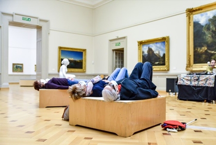 personnes couchées sur structure bois devant tableaux