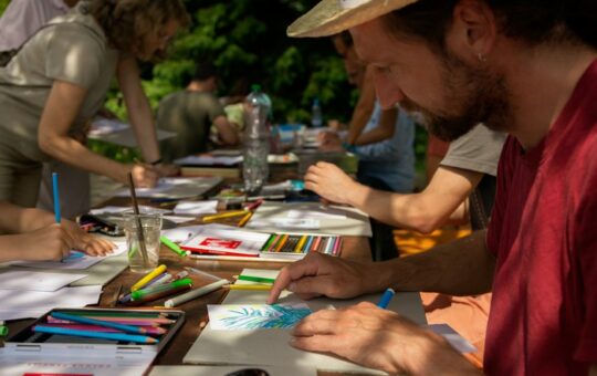 un homme avec un chapeau de paille dessine sur une table