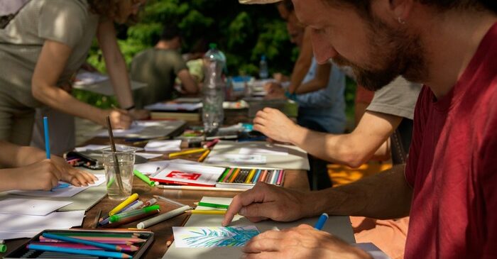 un homme avec un chapeau de paille dessine sur une table