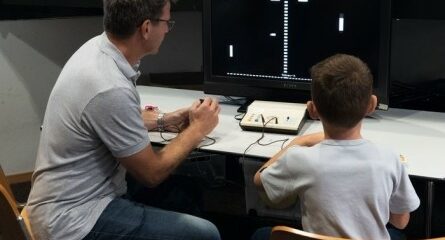 un homme et un jeune garçon jouent à un jeu vidéo sur ordinateur
