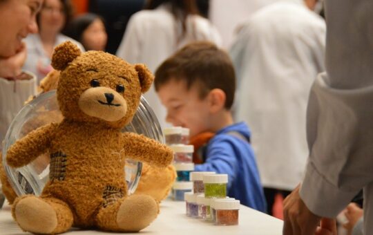 nounours sur une table avec enfants derrière et pots de perles