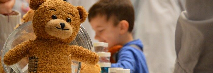 nounours sur une table avec enfants derrière et pots de perles