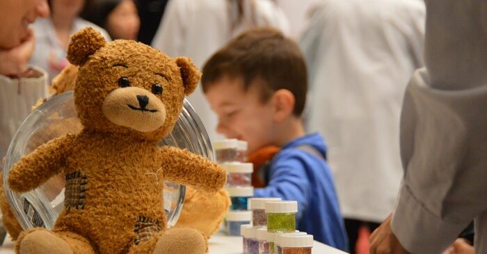 nounours sur une table avec enfants derrière et pots de perles