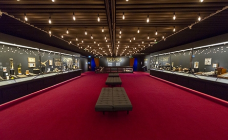 salle exposition avec moquette rouge spot aux plafond et vitrine de chaque côté