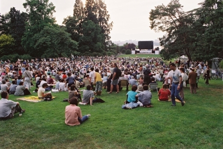 foule assise dans l'herbe devant écran géant