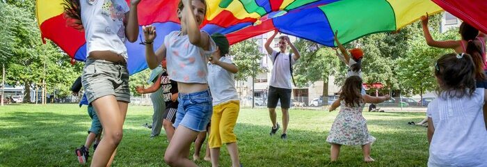 enfants sous un grand drapeau multicolore qu'ils tiennent à bout de bras