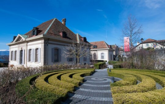 jardin français et bâtiment sous ciel bleu